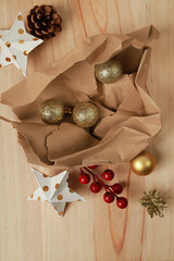 envoltorio de papel marrón con bolas de navidad y estrellas sobre fondo de madera