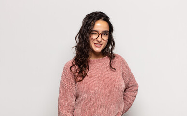 pretty young woman looking happy and friendly, smiling and winking an eye at you with a positive...