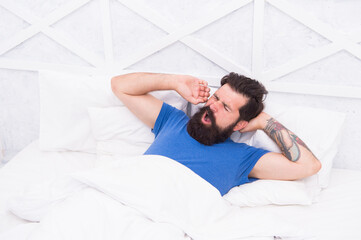 Fototapeta na wymiar yawning man with headache in the morning under blanket in bed, mens health