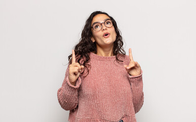 pretty young woman feeling awed and open mouthed pointing upwards with a shocked and surprised look