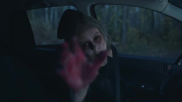 Zombie woman in car attacking you stretching hand to camera