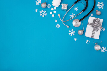 Christmas, medicine greeting card. Blank clipboard and Christmas decorations, pills on a blue background. Medical concept. Copy space, flat lay.