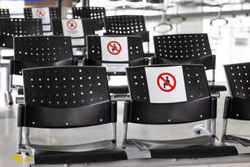 Empty waiting room at an airport during COVID-19 pandemic with social distancing signs on chairs