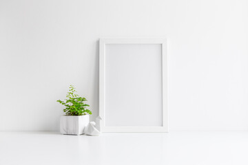 Poster frame mockup and a plant in marble pot near white wall.