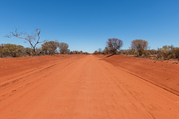 Fototapeta na wymiar A dirt road in the red center of the Australian outback, Northern Territory, Australia.