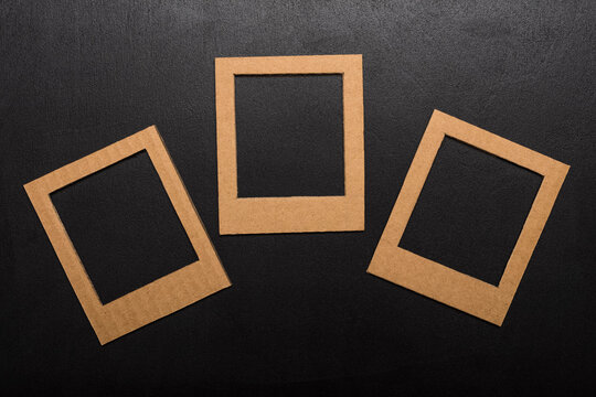 three frames for photos. Kraft cardboard square frame template on black background for family photo. Top view