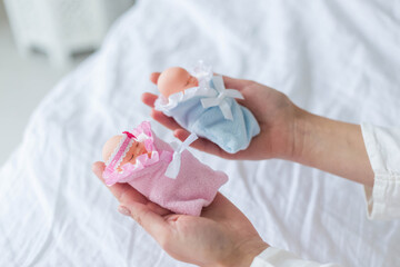 .Female hands hold boy and girl toy babies, IVF gender selection concept.