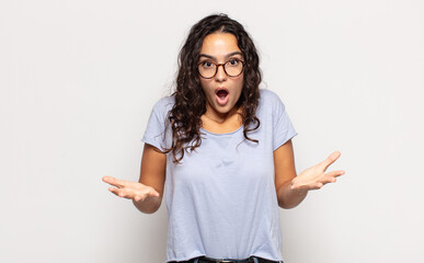 pretty young woman feeling extremely shocked and surprised, anxious and panicking, with a stressed...