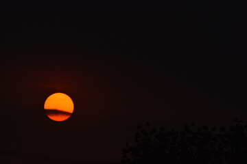 oscuro atardecer con un sol radiante y anaranjado