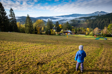 Fototapeta na wymiar kid walking in the mountains, boy wondering beautiful autumn landscape, blue sky in the morning, bohemian forest, czech republic