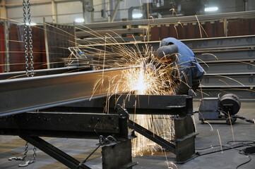 A worker in a factory is cleaning the steel structure of an angle grinder in a workshop.
