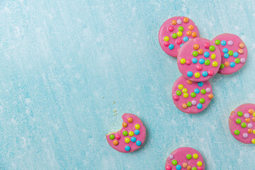 Pink glazed cookies on a blue background/surface. Dutch  cookies called Confettinis. It's a flat...