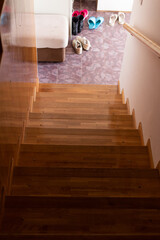 Wooden staricase under day light coming from the door, view from above