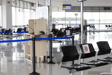 Empty waiting room at an airport during COVID-19 pandemic with social distancing signs on chairs