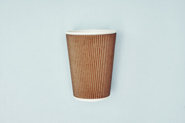 Paper cup in hand on a colored background. Eco-friendly materials in a coffee shop, biodegradable disposable tableware. Close up.