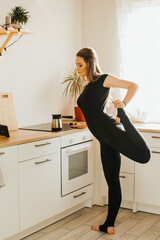 Yogi woman stretches in the kitchen at home. Morning work-out. Sports at home