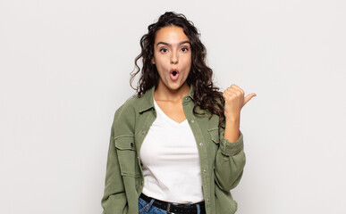 pretty young woman looking astonished in disbelief, pointing at object on the side and saying wow,...