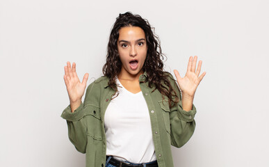 pretty young woman looking shocked and astonished, with jaw dropped in surprise when realizing...