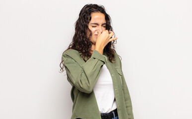 pretty young woman feeling disgusted, holding nose to avoid smelling a foul and unpleasant stench