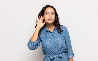 pretty young woman looking serious and curious, listening, trying to hear a secret conversation or...