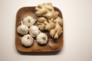 Garlic and ginger on a wooden square plate, isolated