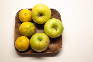 Tangerines and apples on a wooden square plate, isolated
