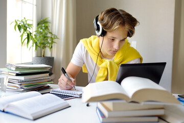 Teenager boy study at home. Online education and distance learning for children. School boy doing his homework using gadgets. Lectures and lessons on the internet for high school students