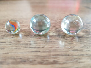 Obraz na płótnie Canvas Glass transparent balls lie on a light wooden table.