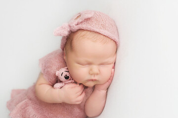 Little newborn baby girl sleeping with a soft toy in his hands, newborn photoshoot