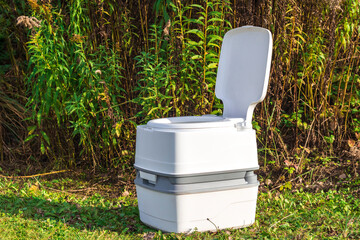 Street lighting. a portable plastic toilet in the foreground. In the back there is a tree.