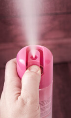 a woman's hand holds a bottle of air freshener and sprays it