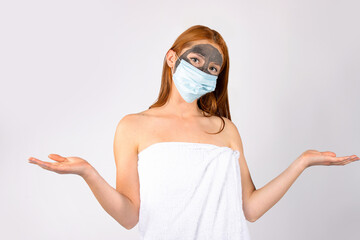 A beautiful redhaired girl, in the salon, with a cosmetic mask on her face and for a pandemic is...