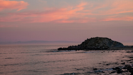 Fototapeta na wymiar Beautiful sunset on a pristine beach with rocks in the background