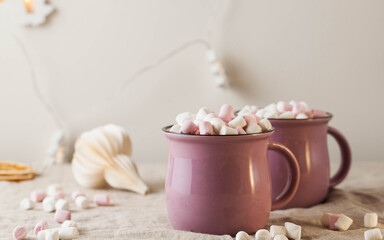 Fototapeta na wymiar Hot chocolate with marshmallows in mugs on a linen tablecloth with Christmas toy. concept of winter home away from home