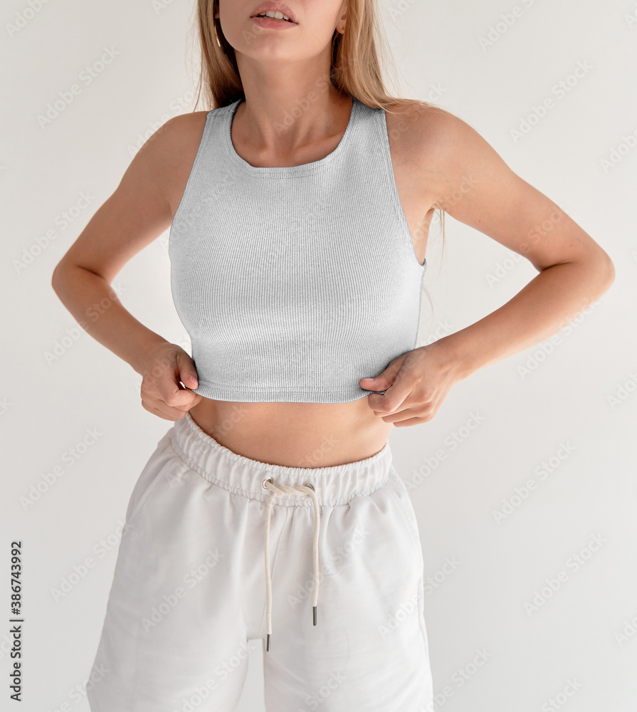 Wall mural girl wears white crop top and white shorts. studio shooting of young woman in casual street wear