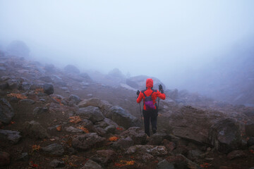 The tourist overcomes a difficult transition. Hiking in bad weather, through rain and fog. Active outdoors people lifestyle