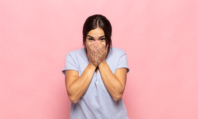 pretty young woman happy and excited, surprised and amazed covering mouth with hands, giggling with...