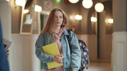 Beautiful upset woman student walking with books and backpack indoors - Powered by Adobe