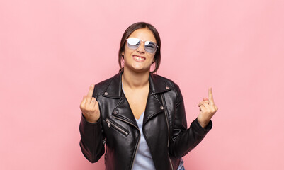 pretty young woman feeling provocative, aggressive and obscene, flipping the middle finger, with a...