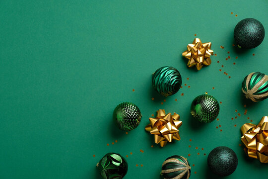 Christmas or New Year decorations on green background. Flat lay, top view green baubles and gold tinsel. Christmas frame. - Powered by Adobe
