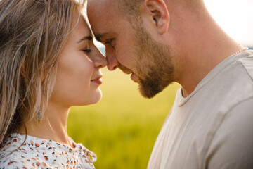 Loving couple on a green lawn. The guy and the girl are kissing.