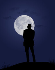 A man in a fedora stands on a hilltop watching a full moon at night.