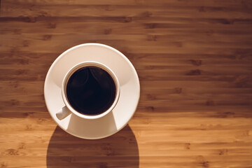 Cup of black coffee on bamboo desk