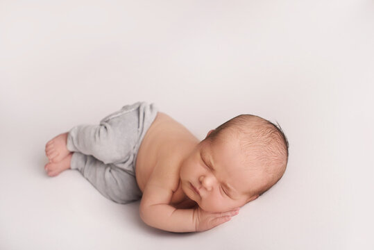 newborn photoshoot of a small newborn baby sleeps on his tummy, propping his cheek with his palm, a photo session of a newborn little baby