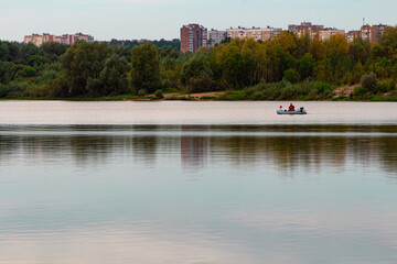 Two people in a pond on the background of the banks of the city with houses