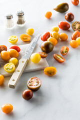 Colourful cherry tomatoes on a marble cutting board against a white background.