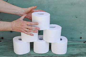 Eine Frau nimmt sich eine Rolle Klopapier von einem Stapel. Maßeneinkauf von Toilettenpapier
