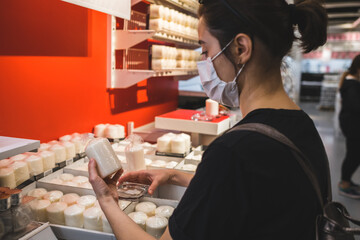 Young lady in a mask shopping at the grocery store for celebration and authentic decor.