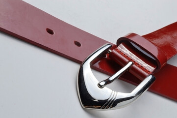 red women's belt with a chrome plaque on a white background. close-up.