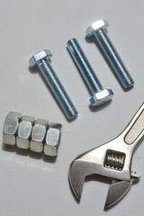 screw-nut of different sizes, bolts and adjustable spanner. White background.